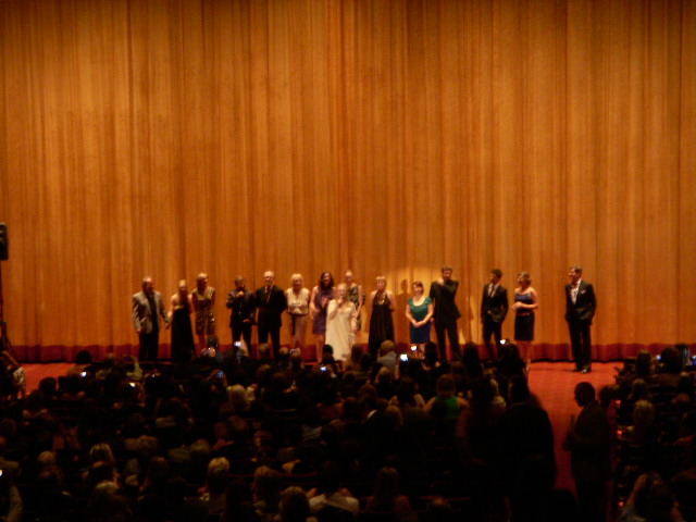 A blurry photo of the Mamma Mia! cast lined up in front of a curtain and screen