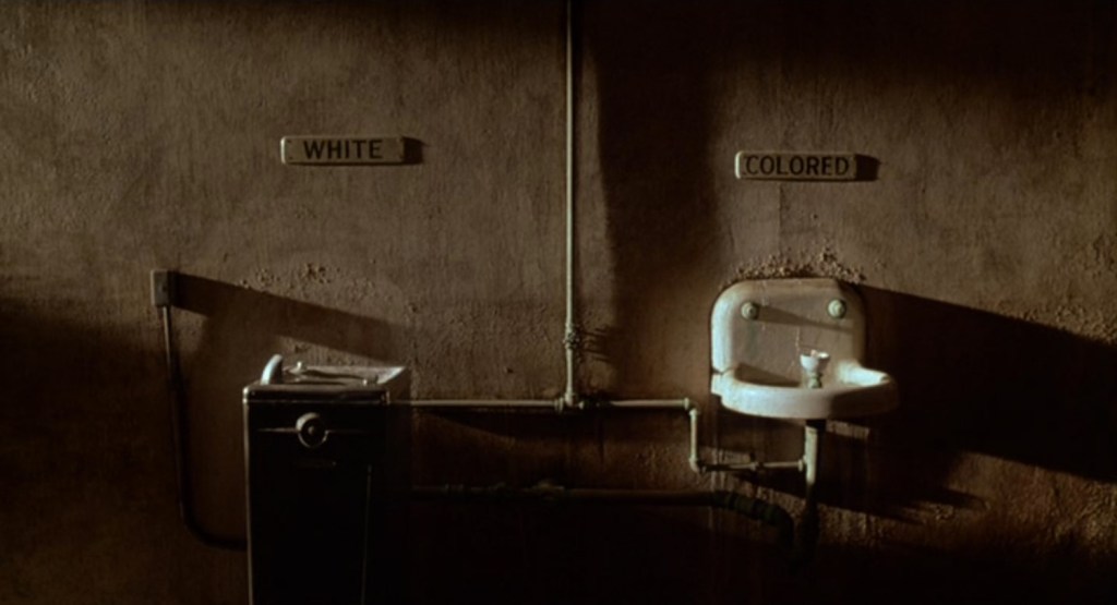 Opening shot from Mississippi Burning showing separate drinking fountains labeled "White" and "Colored."